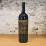 Botella de vino tinto Cavallo Rosso Di Camillo junto a copa servida sobre fondo rústico italiano