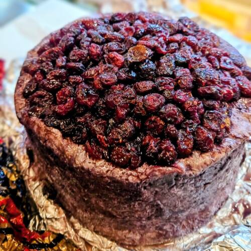 Pieza de queso azul italiano Blu 61 afinado en vino Raboso y cubierto de arándanos rojos sobre tabla gourmet bronce en world cheese award 2025