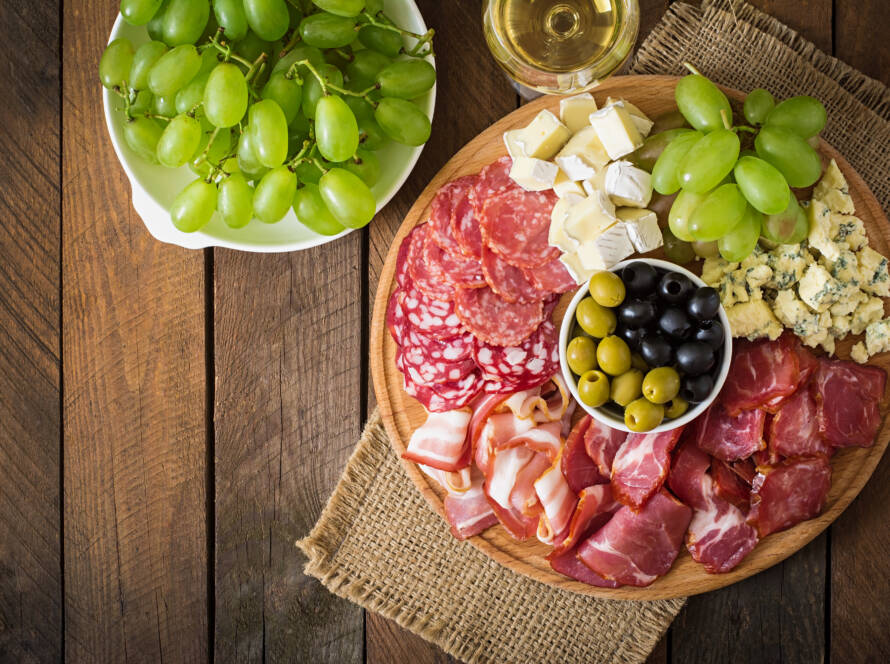 tabla quesos embutidos italianos sobre mesa de madera con acompañamientos
